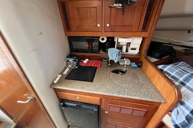 Slide: The Image of Compact kitchen area in a 2001 Rampage Express 30 Open boat, featuring wooden cabinetry. - 41