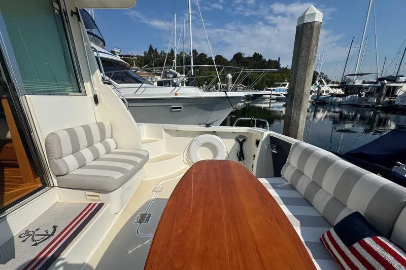 Slide: The Image of 2016 Sabre Craft Salon Express yacht interior with striped seating and wooden table at marina. - 20