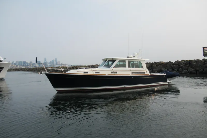 Slide: The Image of 2016 Sabre Salon Express yacht cruising near rocky shoreline with city skyline in background. - 41