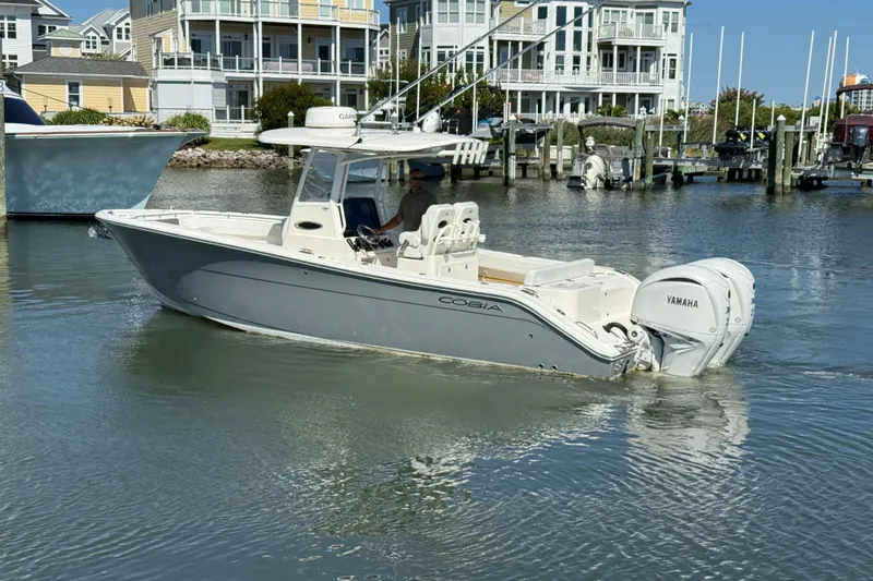 Slide: The Image of 2023 Cobia 280 Center Console boat with Yamaha engine in a marina setting. - 1