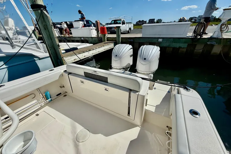 Slide: The Image of 2023 Cobia 280 Center Console boat docked, featuring dual outboard engines. - 12
