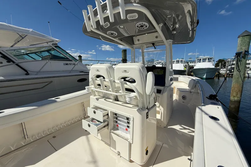 Slide: The Image of 2023 Cobia 280 Center Console boat docked, featuring modern seating and control panel. - 14