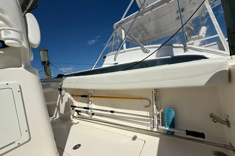 Slide: The Image of 2023 Cobia 280 Center Console boat interior with fishing rod holders and clear blue sky. - 16