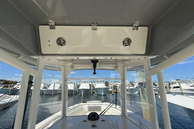 Slide: The Image of 2023 Cobia 280 Center Console boat interior view at marina, showcasing helm and storage. - 17