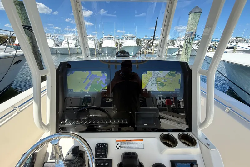 Slide: The Image of 2023 Cobia 280 Center Console boat dashboard with navigation screens in marina. - 18