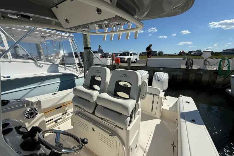 Slide: The Image of 2023 Cobia 280 Center Console boat docked, featuring comfortable seating and steering wheel. - 20