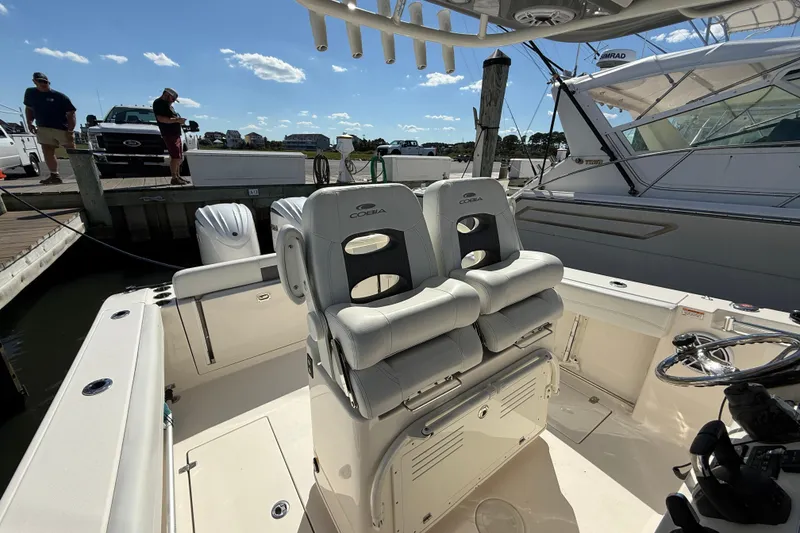 Slide: The Image of 2023 Cobia 280 Center Console boat interior with dual seats and docked setting. - 21