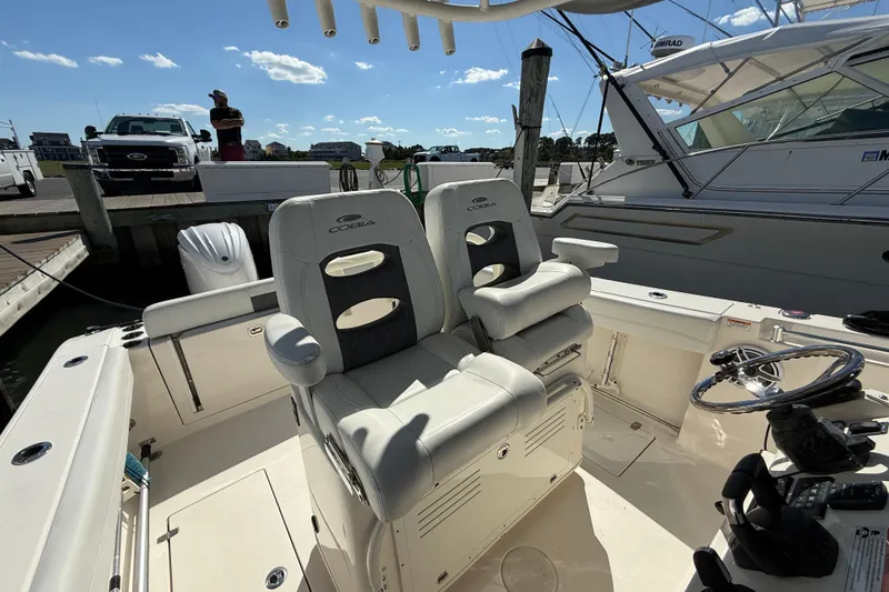 Slide: The Image of 2023 Cobia 280 Center Console boat interior with dual seating at marina. - 23