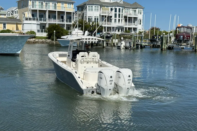 Slide: The Image of 2023 Cobia 280 Center Console boat with twin Yamaha engines in a marina setting. - 3