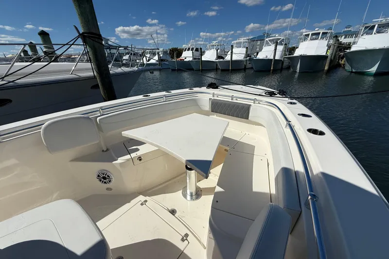 Slide: The Image of 2023 Cobia 280 Center Console boat docked, featuring spacious seating and a triangular table. - 38