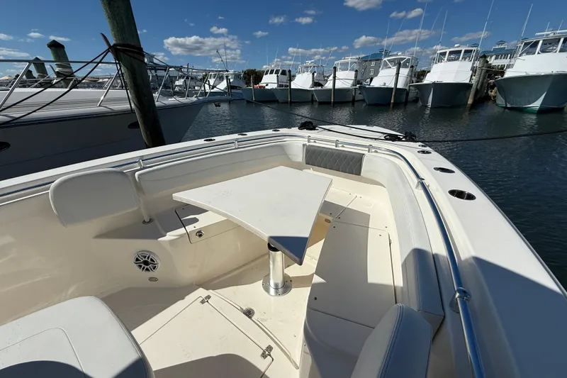 Slide: The Image of 2023 Cobia 280 Center Console boat docked, featuring a spacious seating area and table. - 39