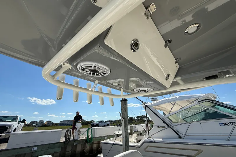 Slide: The Image of 2023 Cobia 280 Center Console boat with rod holders and speakers at a marina. - 49