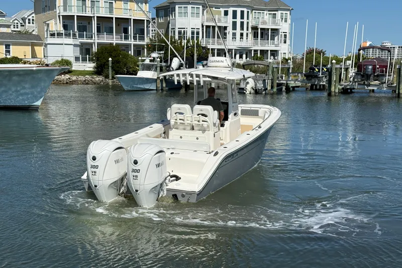 Slide: The Image of 2023 Cobia 280 Center Console boat with twin Yamaha engines in a marina setting. - 6