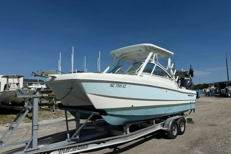 Slide: The Image of 2023 World Cat 230 DC boat on trailer at marina under clear blue sky. - 1