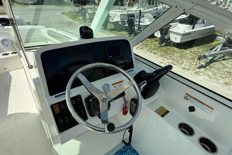 Slide: The Image of 2023 World Cat 230 DC boat helm with steering wheel and controls. - 12