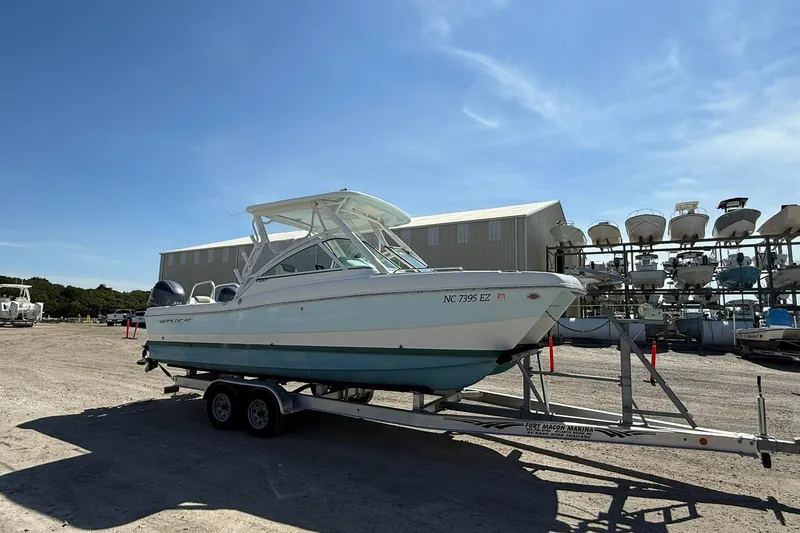 Slide: The Image of 2023 World Cat 230 DC boat on trailer at marina under clear blue sky. - 5