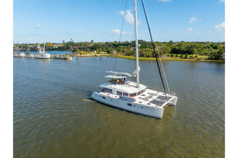 Slide: The Image of 2012 Lagoon 560 catamaran sailing on a calm river under a clear blue sky. - 132