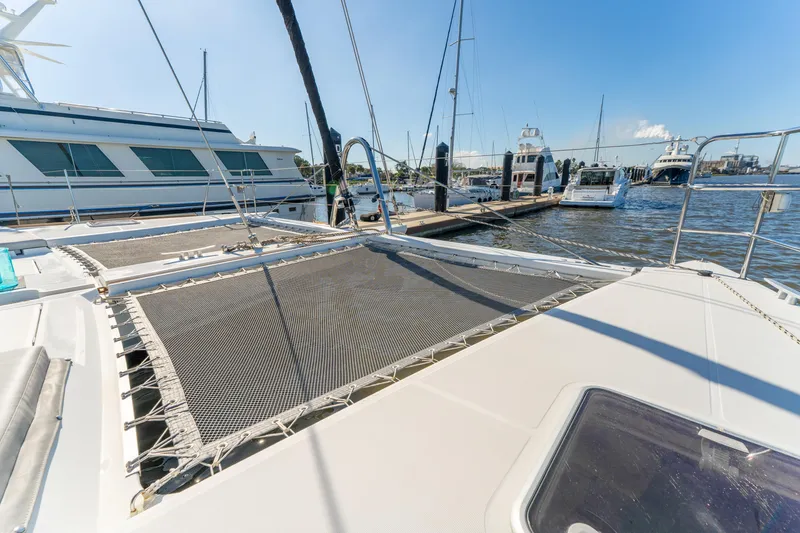 Slide: The Image of 2012 Lagoon 560 catamaran docked at marina, featuring spacious deck and netting. - 17