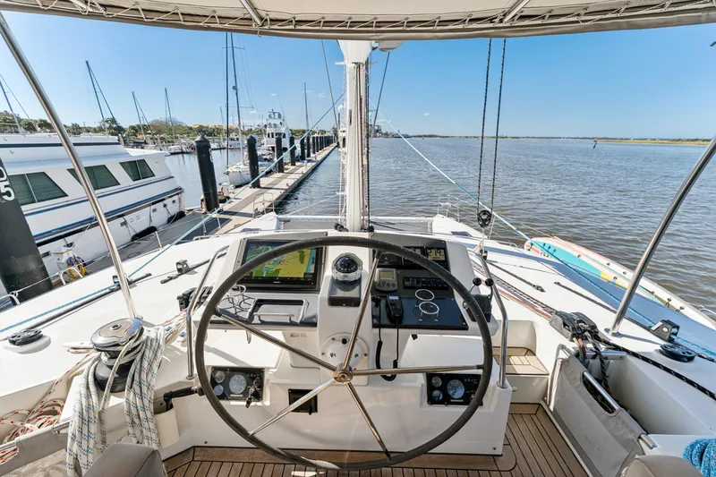 Slide: The Image of Cockpit view of 2012 Lagoon 560 yacht docked at marina, featuring steering wheel and navigation equipment. - 35