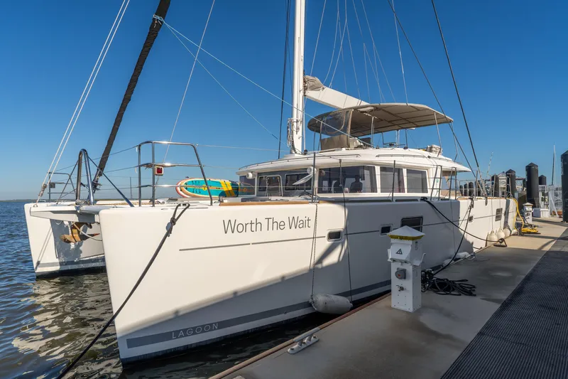 Slide: The Image of 2012 Lagoon 560 catamaran "Worth The Wait" docked at marina under clear blue sky. - 5