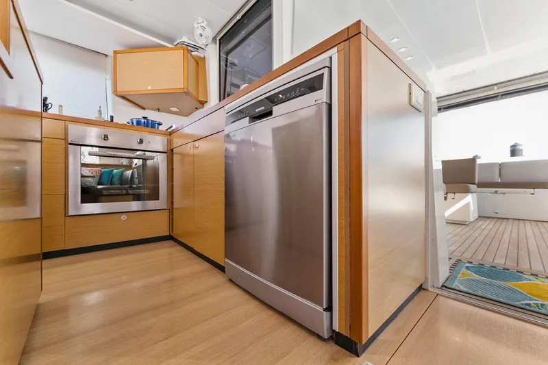 Slide: The Image of Modern kitchen interior on 2012 Lagoon 560 yacht, featuring wood cabinetry and stainless steel appliances. - 62