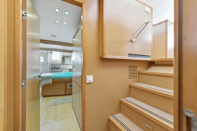 Slide: The Image of Interior of 2012 Lagoon 560 yacht, featuring wooden stairs and a cozy bedroom. - 98