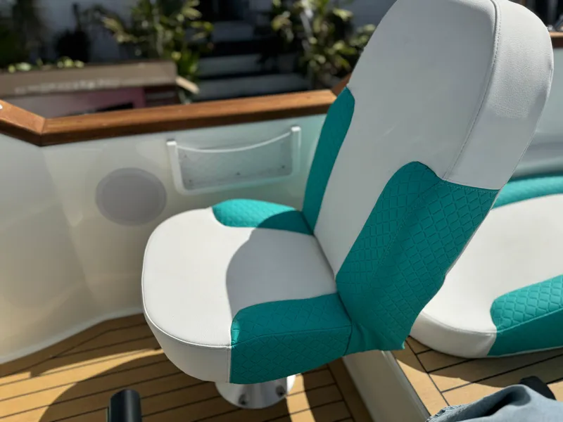 Slide: The Image of White and teal boat seat on wooden deck, surrounded by greenery. - 18