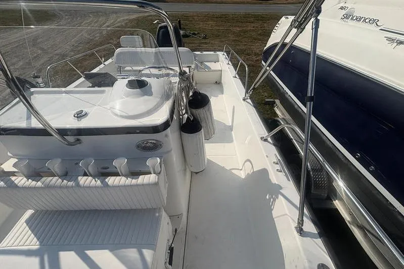 Slide: The Image of 2012 Boston Whaler 210 Montauk boat interior with seating and console, docked beside another vessel. - 10