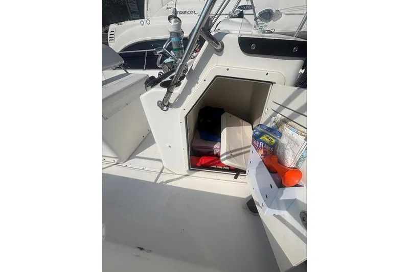 Slide: The Image of 2012 Boston Whaler 210 Montauk boat interior with open storage compartment and various items. - 15
