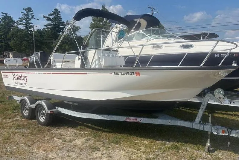 Slide: The Image of 2012 Boston Whaler 210 Montauk boat on trailer, parked outdoors under blue sky. - 3