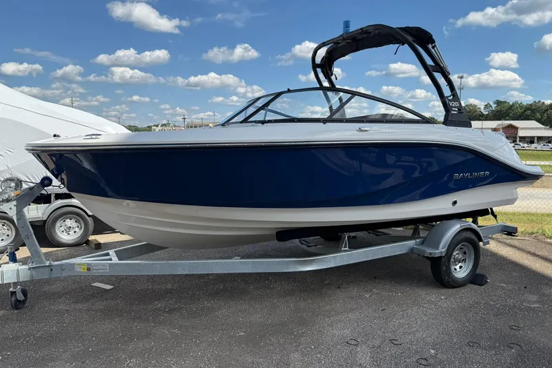 Slide: The Image of 2025 Bayliner V20i boat on trailer under a blue sky with clouds. - 1