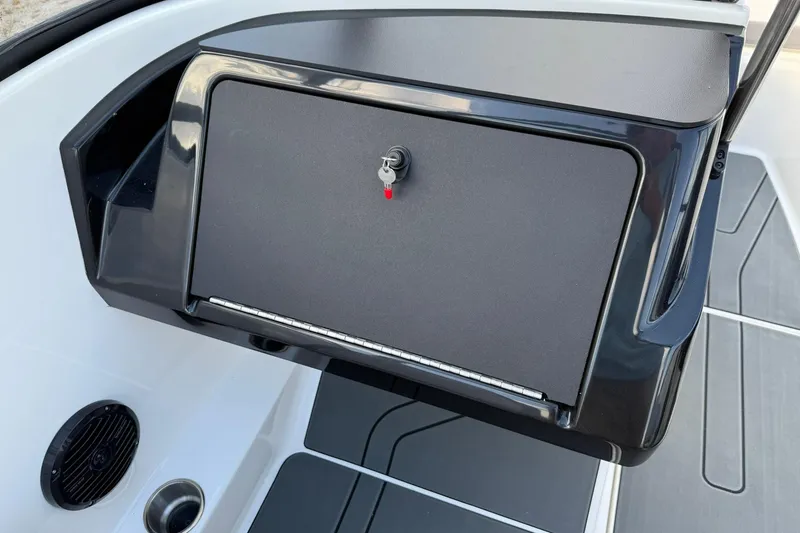 Slide: The Image of 2025 Bayliner V20i boat dashboard with secure storage compartment and key. - 17