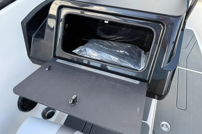 Slide: The Image of 2025 Bayliner V20i boat storage compartment with open lid and visible contents. - 18