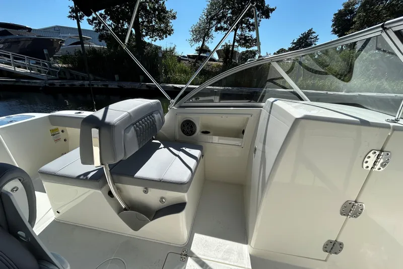 Slide: The Image of 2026 Cobia 220 Dual Console boat interior with seating and storage, docked near water. - 11