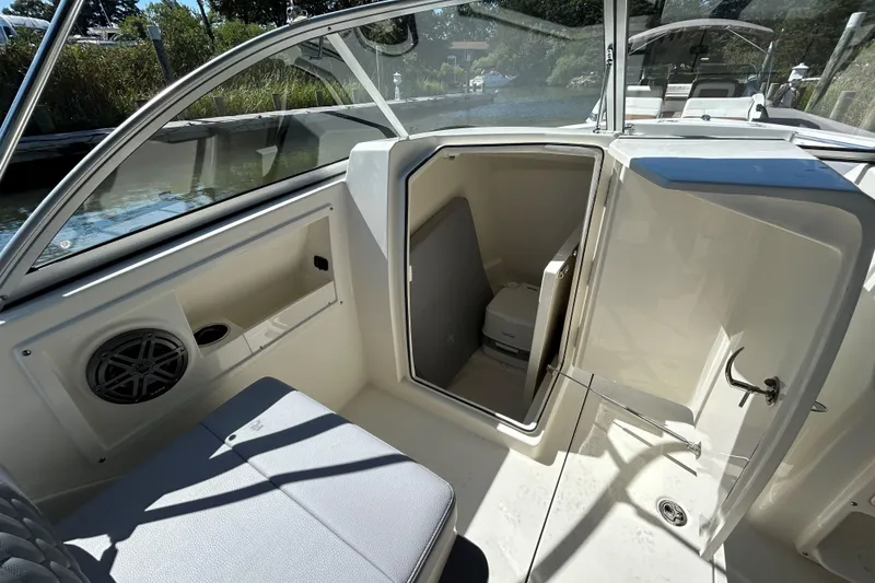 Slide: The Image of 2026 Cobia 220 Dual Console boat interior with open storage compartment and seating. - 12