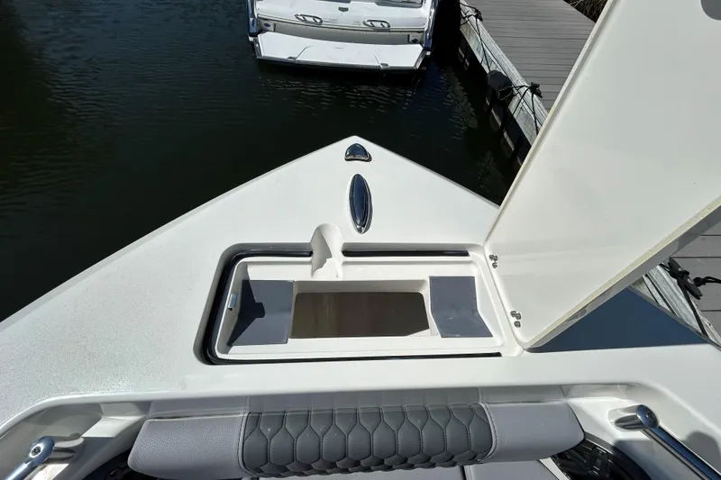 Slide: The Image of 2026 Cobia 220 Dual Console boat with open storage compartment at dock. - 17