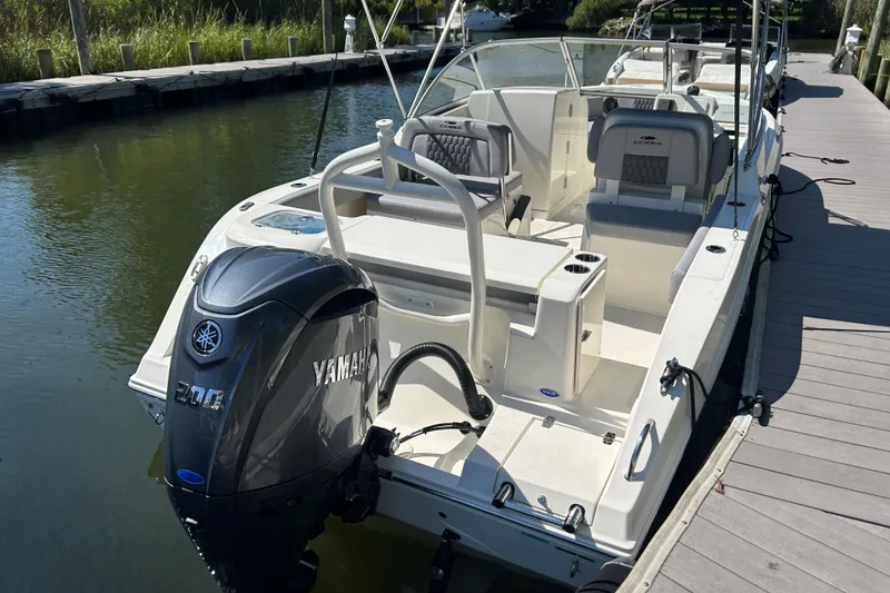 Slide: The Image of 2026 Cobia 220 Dual Console boat docked, featuring Yamaha outboard motor. - 2
