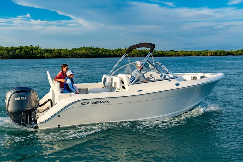 Slide: The Image of 2026 Cobia 220 Dual Console boat cruising on a sunny day with passengers. - 20