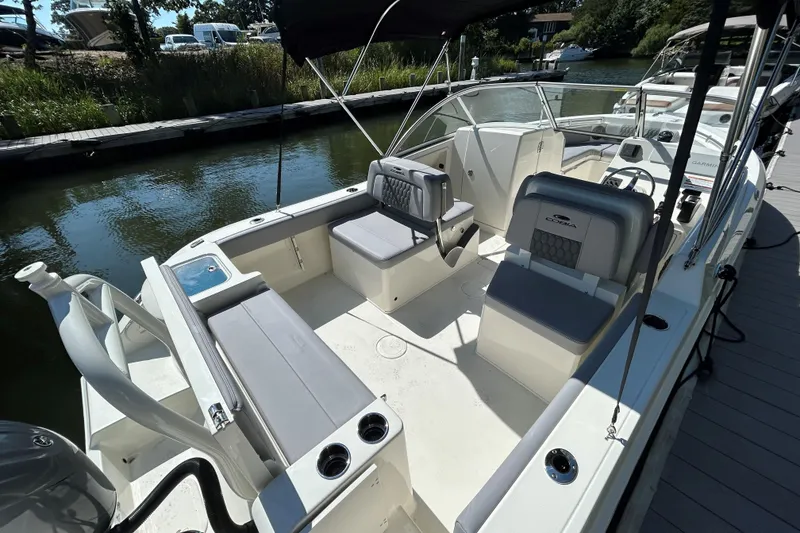 Slide: The Image of 2026 Cobia 220 Dual Console boat interior with seating and console, docked by the water. - 4