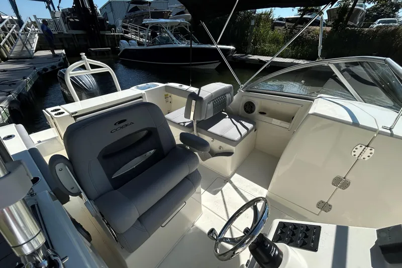Slide: The Image of 2026 Cobia 220 Dual Console boat interior with steering wheel and seating. - 7