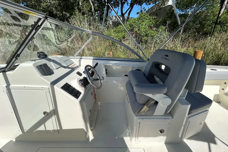 Slide: The Image of 2026 Cobia 220 Dual Console boat interior with steering wheel and cushioned seating. - 8