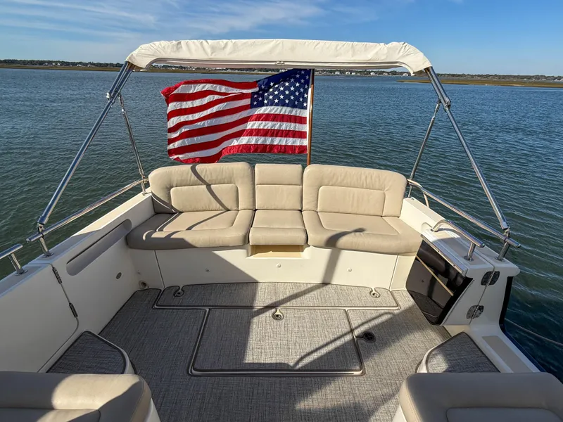 Slide: The Image of 2015 MJM 36z Downeast boat with American flag, beige seating, and calm waters. - 11