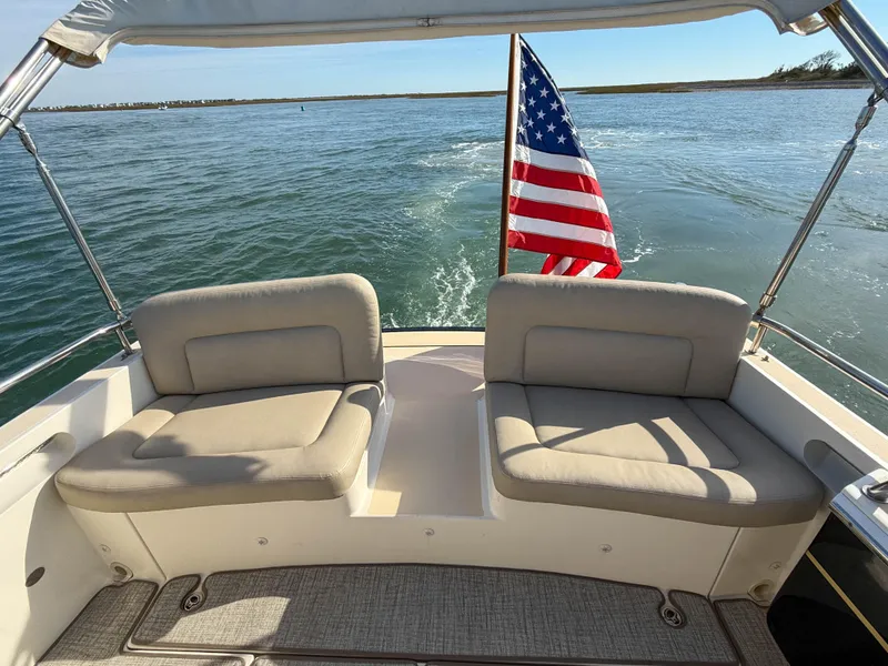 Slide: The Image of 2015 MJM 36z Downeast boat with American flag, beige seating, and ocean view. - 12