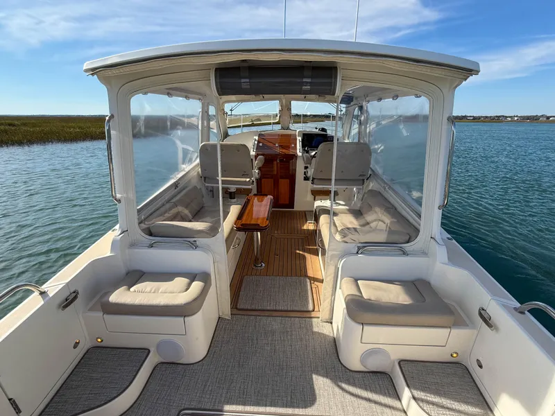 Slide: The Image of 2015 MJM 36z Downeast boat interior with seating and wooden flooring on calm water. - 13