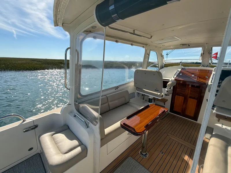 Slide: The Image of 2015 MJM 36z Downeast boat interior with seating and wooden table on a sunny day. - 16