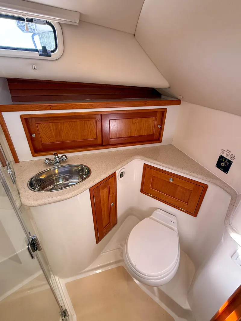 Slide: The Image of 2015 MJM 36z Downeast yacht bathroom with sink, toilet, and wooden cabinets. - 38