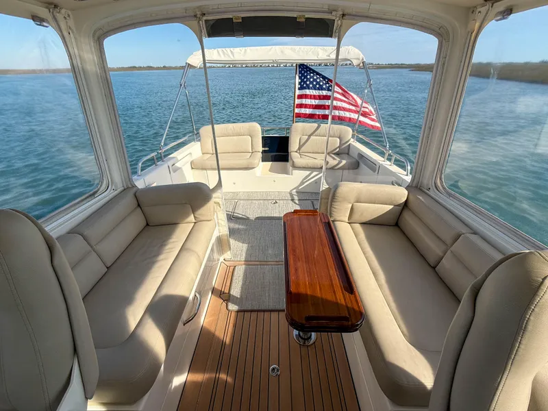 Slide: The Image of 2015 MJM 36z Downeast boat interior with American flag, spacious seating, and wooden table. - 40