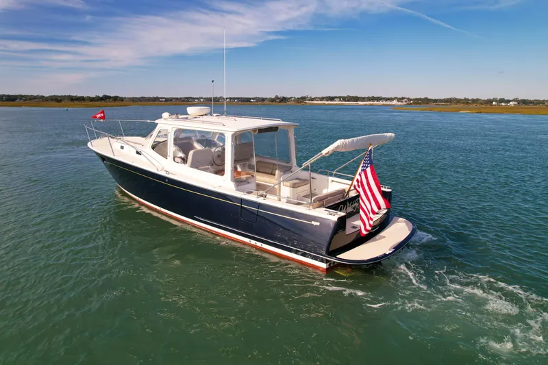 Slide: The Image of 2015 MJM 36z Downeast boat cruising on calm waters with American flag. - 5