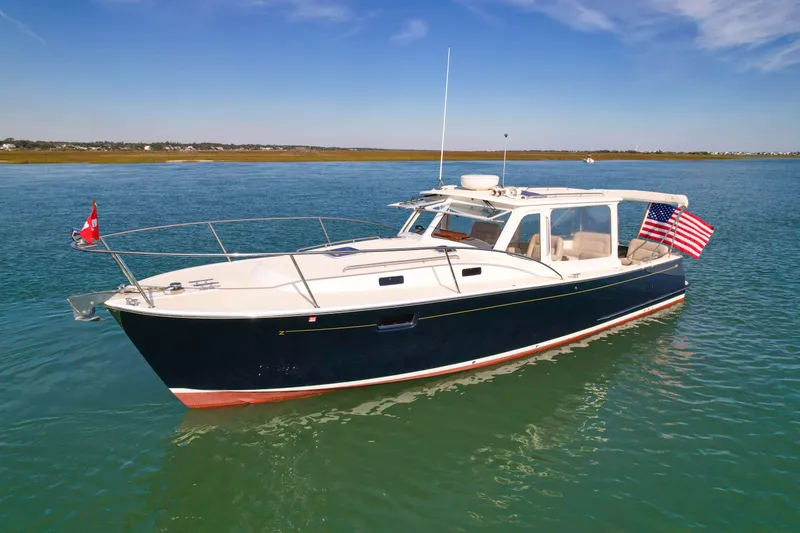 Slide: The Image of 2015 MJM 36z Downeast boat on calm water, featuring flags and sleek design. - 6
