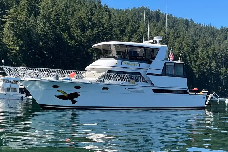 Slide: The Image of 1991 Californian 52 Cockpit Motor Yacht on serene water, surrounded by lush forest. - 1